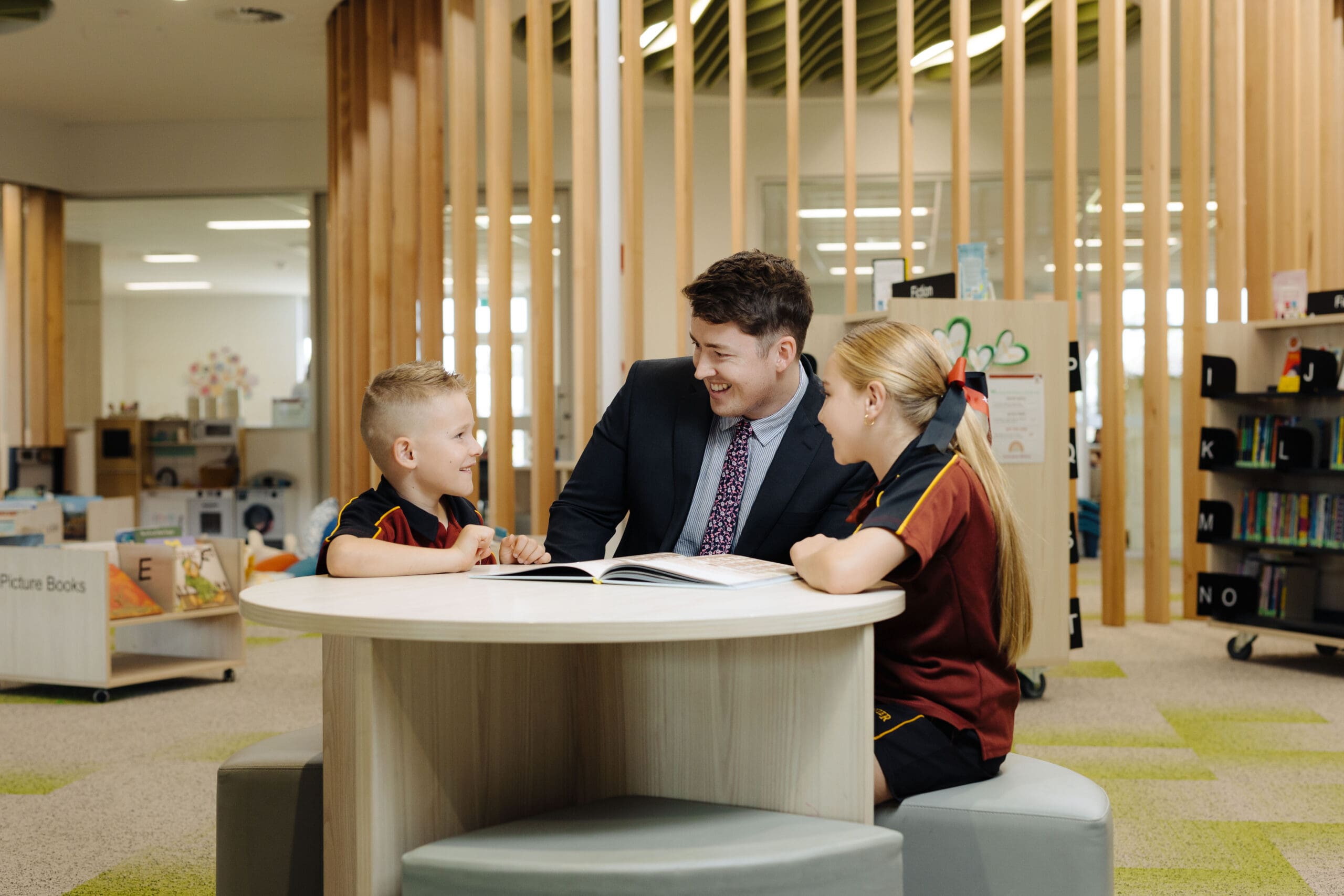 Teacher guiding students through a book in the Two Wells Campus library. 