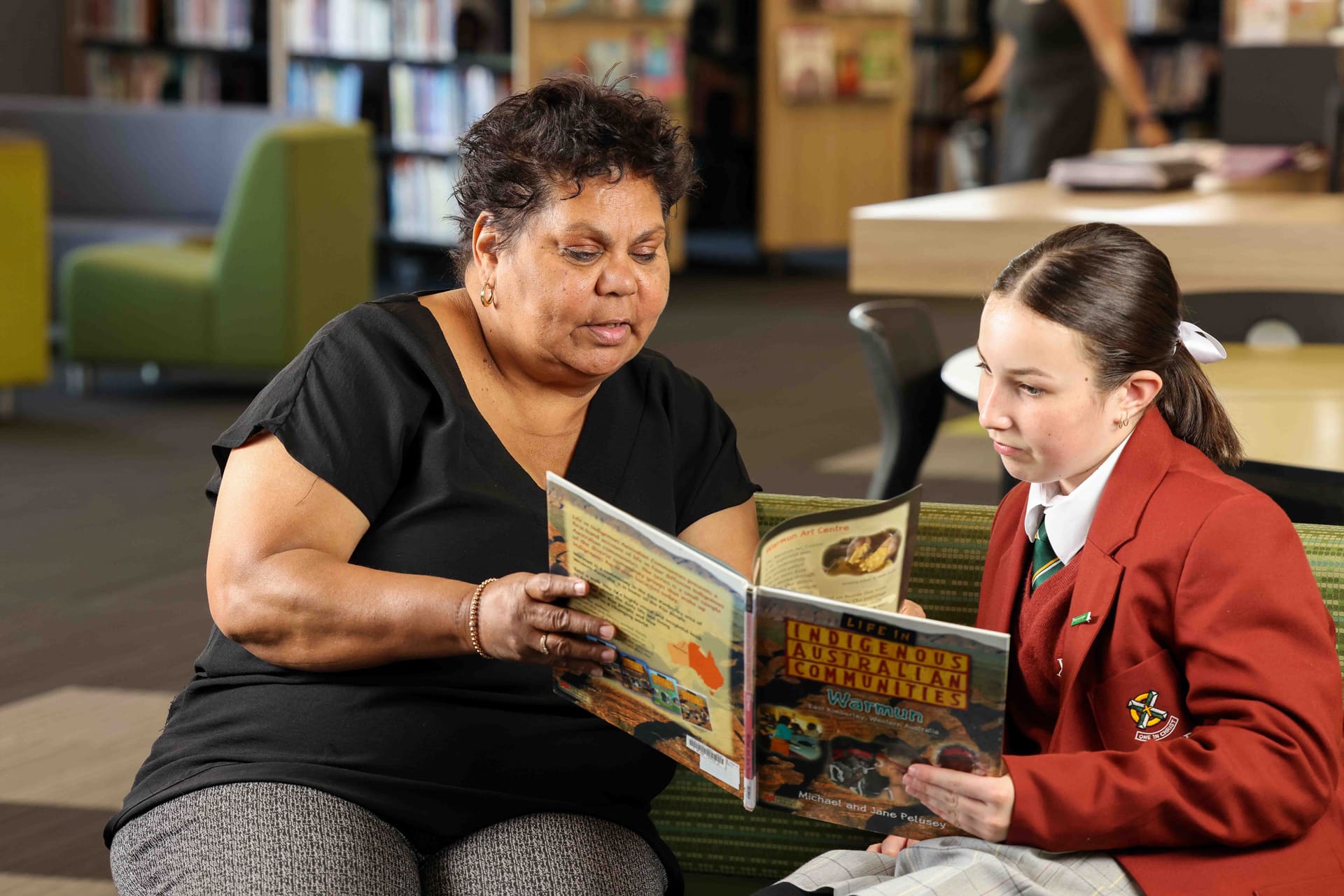 Xavier College's Aboriginal and Torres Strait Islander Coordinator educating a student through a book. 