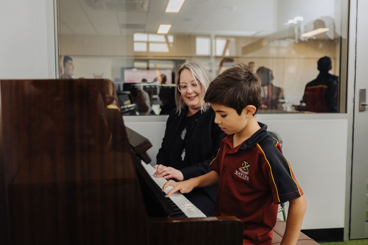 A music teacher showing a early years student how to play the piano