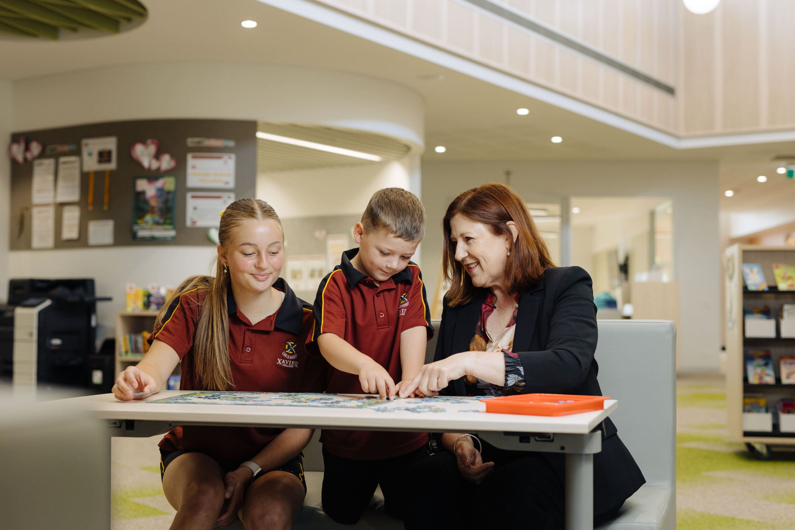 Two students sitting at a table with their teacher completing a task.