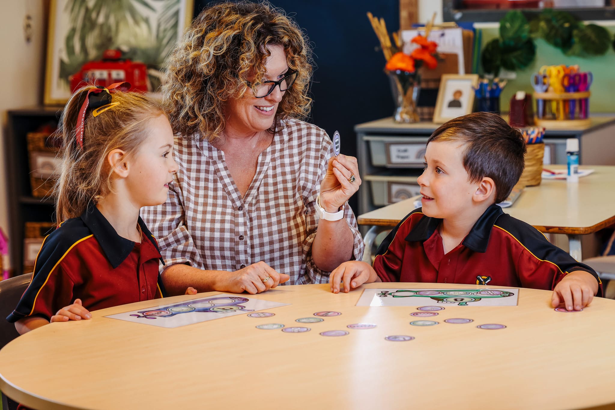 A staff member/volunteer helping primary students with their work. 