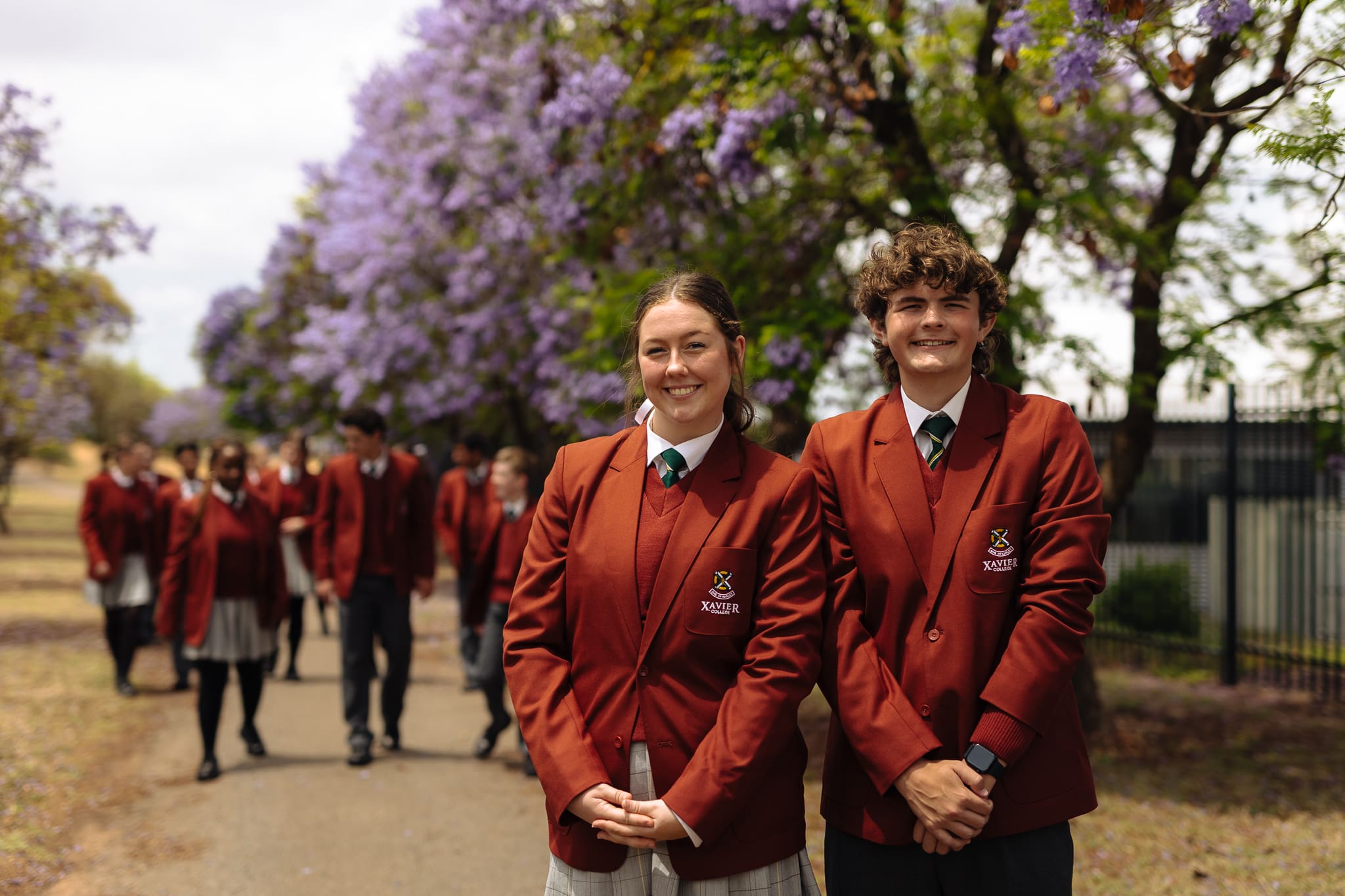 Senior students in formal winter uniform smiling at the camera. 